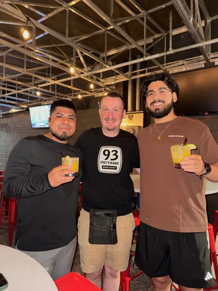 Three runners raising drinks inside 93 Octane