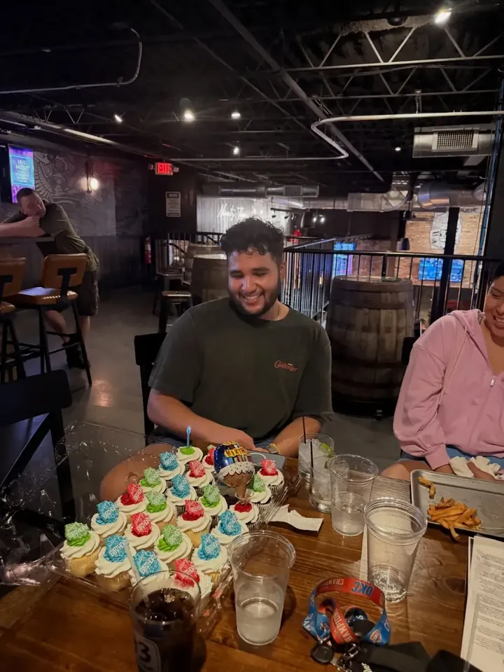 A runner smiling over a table of birthday cupcakes