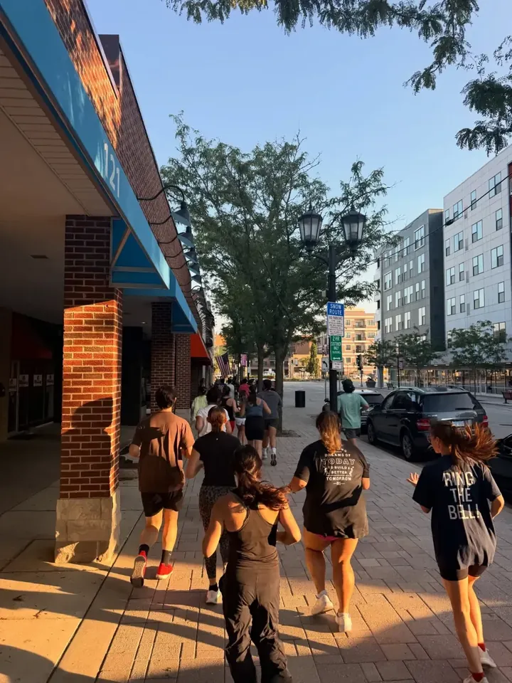 Runners heading down a downtown sidewalk in golden light