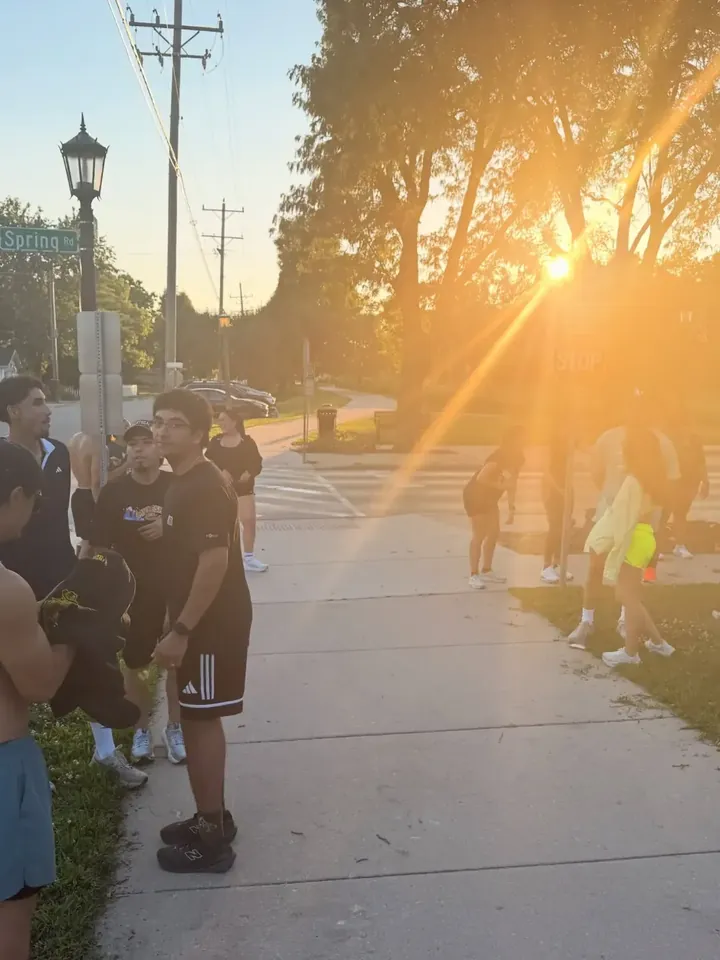 Runners on a sidewalk with the sun setting through the trees