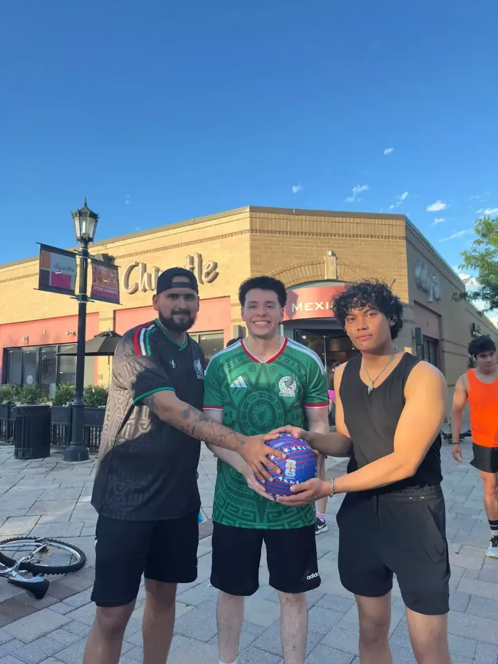 Three runners in soccer jerseys holding a ball outside Chipotle