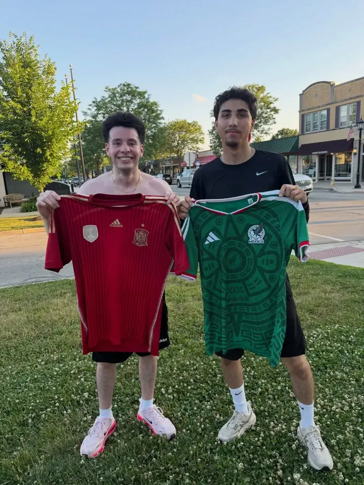 Two runners holding up Spain and Mexico jerseys on the grass